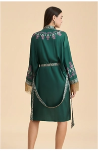 Détail du peignoir kimono vert avec broderie florale et manches à pompons dorés