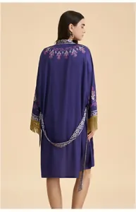 Détail de la broderie florale ethnique et des glands dorés au dos d'un peignoir kimono bleu