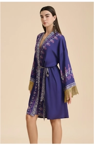 Détail de la broderie florale et des franges dorées sur un peignoir en satin violet
