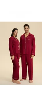 Detail of dark red couple's satin pajama set featuring classic white contrast piping