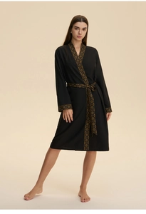 Detail of a black kimono bathrobe featuring golden geometric texture on the sleeves