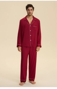 Detail of burgundy satin men's pajama set featuring white piping and silky fabric texture