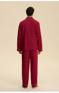 Detail of burgundy satin men's pajama set showing white contrast piping on cuffs and hem