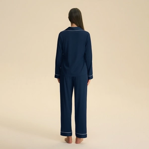 Women's dark blue satin pajama set featuring long sleeves and pants with white piping trim