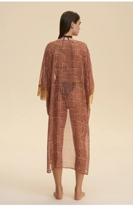 Macro shot of ethnic geometric print on sheer chiffon robe with gold fringe tassels