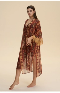Detail eines böhmischen Chiffon-Strandkleids mit Ethno-Drucken und Fransenverzierung