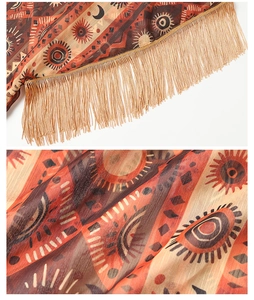 Makro-Detail des Boho-Chiffon-Morgenspiels mit Ethno-Sonne-Mond-Muster und Goldfransen