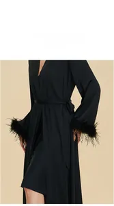 Détail des manches du peignoir en satin noir avec bordure en plumes luxueuses amovibles