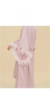 Detailed macro view of luxurious light pink satin robe sleeves featuring elegant feather trim