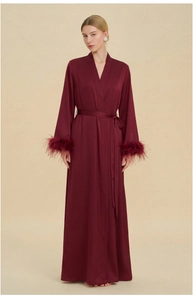 Détail d'un peignoir en satin bordeaux de luxe avec bordure en plumes aux manches