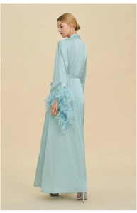 Detail of luxury ice blue silk robe featuring elegant feather trim on sleeve cuffs