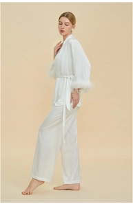 Detail of detachable white feather cuffs on a luxury pearl white satin pajama sleeve