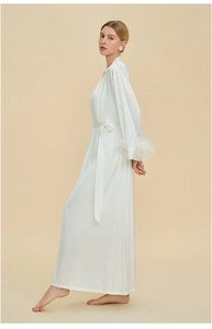 Detail view of luxurious white silk robe featuring elegant ostrich feather trim on cuffs