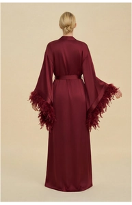 Macro view of burgundy satin robe featuring luxury feather trim on the wide long sleeves