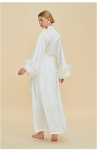 Detail of white satin robe with luxurious detachable feather cuffs and belted waist design