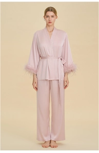 Detail view of pink satin pajama set featuring luxurious feather cuffs and waist tie