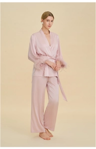 Detail view of pink silk pajamas featuring luxurious feather trim on long sleeve cuffs