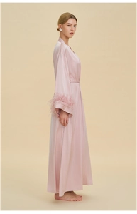 Detail of the elegant light pink silk robe featuring removable feather trim on the sleeves