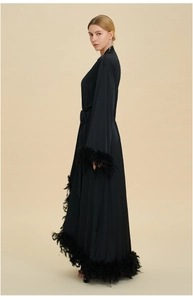Detailed side view of long black silk robe with luxurious ostrich feather cuffs and hem
