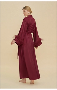 Detail of burgundy satin robe featuring luxurious ostrich feather trim on the sleeves
