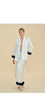 Detail of white silk pajamas with black piping and 3D floral accents on cuffs