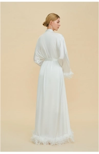 Detail of elegant white satin robe featuring luxurious feather trim on sleeves and hemline