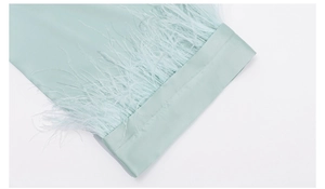 Detailed view of mint green satin fabric featuring elegant feather trim decoration