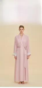 Dettaglio della vestaglia lunga in raso rosa con pizzo bianco fine sui polsini