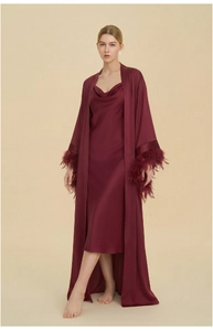 Close-up of elegant burgundy satin robe set featuring feather trim on long sleeves and glossy silk