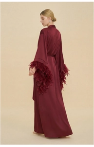 Detail of wine red satin robe featuring elegant feather trim on the sleeve cuffs