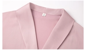 Dettaglio macro del colletto in raso rosa con etichetta S e trama in seta liscia