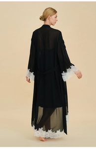 Detail of black chiffon robe with elegant white lace trim on sleeves and back