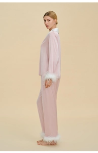 Détail d'un pyjama de luxe en satin rose avec d'élégantes bordures en plumes blanches