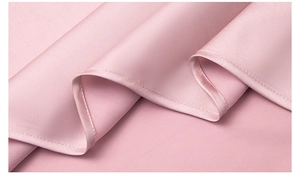 Dettaglio di pigiama in seta rosa con finitura satinata e cuciture dell'orlo pregiate