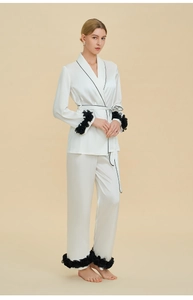 Detailed view of white silk pajamas with black piping and floral cuffs for women