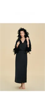 Détails d'un peignoir de luxe en satin noir avec bordure en plumes et capuche