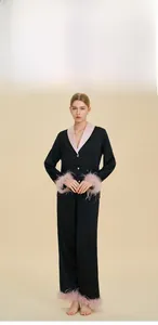 Detail view of luxury black pajamas featuring elegant pink feather cuffs and satin finish