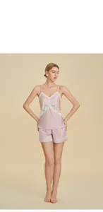 Détail d'un ensemble pyjama en satin rose avec dentelle blanche sur le haut et short