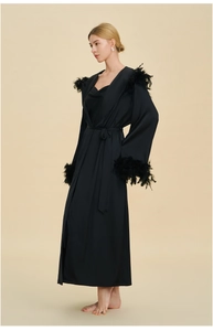 Détail de la robe en satin noir luxueux avec bordure en plumes élégante aux épaules et poignets