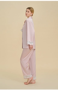 Detailed view of delicate white lace embroidery on pink silk pajamas sleeve and trousers