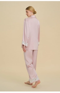 Detailed view of white lace trim on the sleeve and hem of pink satin pajama set