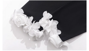 Detailed view of 3D white chiffon flowers sewn onto black pajamas sleeve cuff fabric