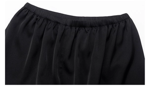 Detail of elegant black pajama pants featuring an elastic waistband and silk-like fabric