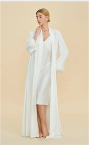 Detailed shot of white satin pajama set with elegant feather trim on the sleeves