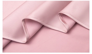 Close-up of pink satin nightgown fabric showing soft texture and fine hem stitching