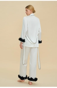 Détail du vêtement de nuit en satin blanc avec fleurs noires et longs rubans au dos