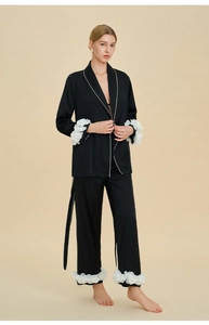 Détail d'un pyjama en soie noire avec poignets à fleurs 3D et élégant passepoil contrasté