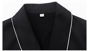 Détail du vêtement de détente en satin noir avec col en V et passepoil blanc contrasté