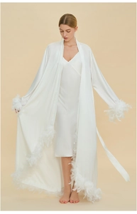 Detailed close-up of white silk robe with luxury feather trim on sleeves and hemline