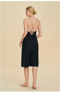 Detail of cross-back straps and elegant bow tie on a black satin slip dress